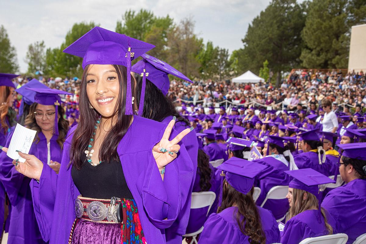 当地女毕业生微笑着，在毕业典礼上做了一个和平手势